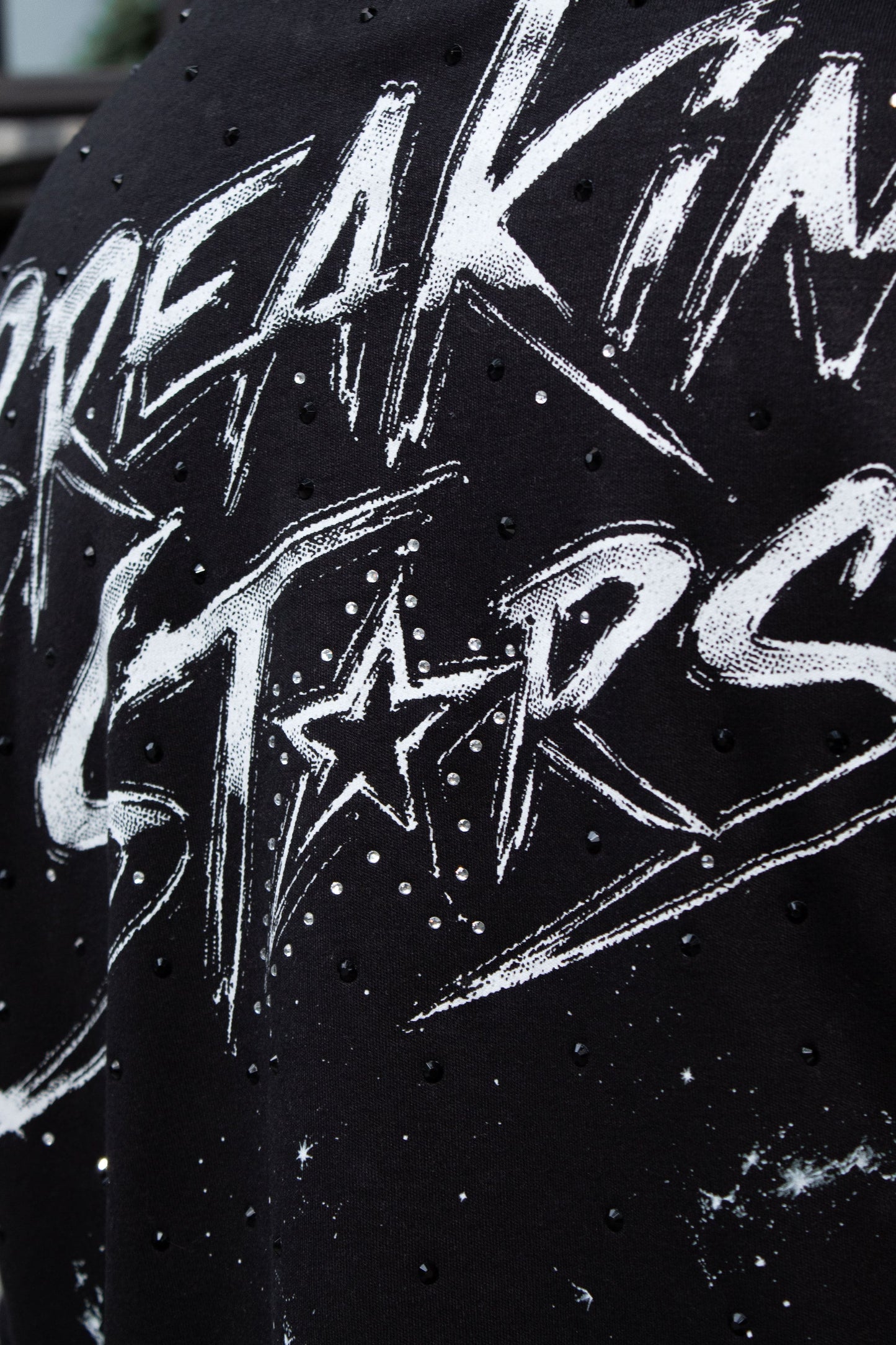 Playera streetwear negra con pedrería negra, diseño espacial Breaking Stars y corte over