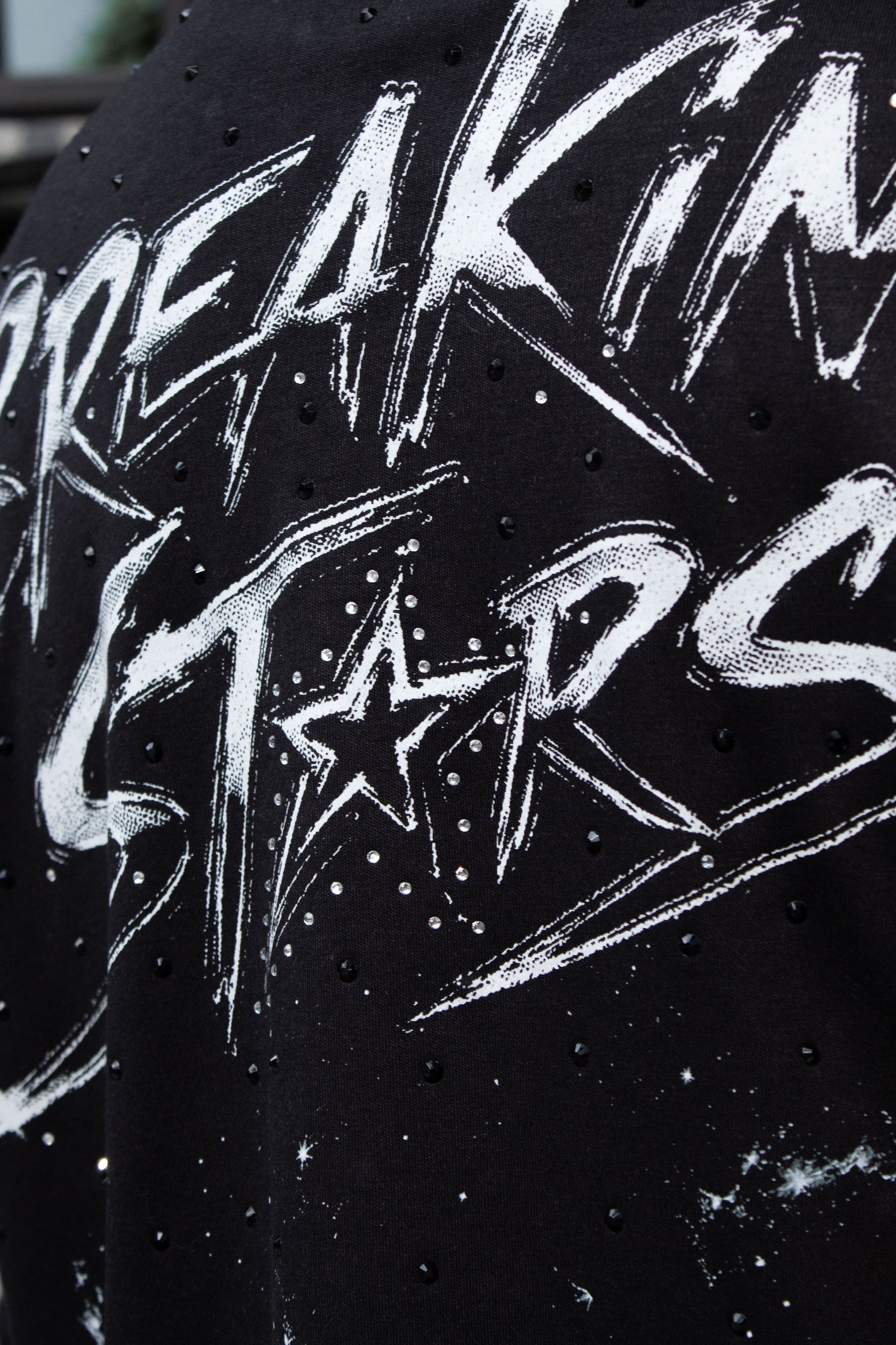 Playera streetwear negra con pedrería negra, diseño espacial Breaking Stars y corte over