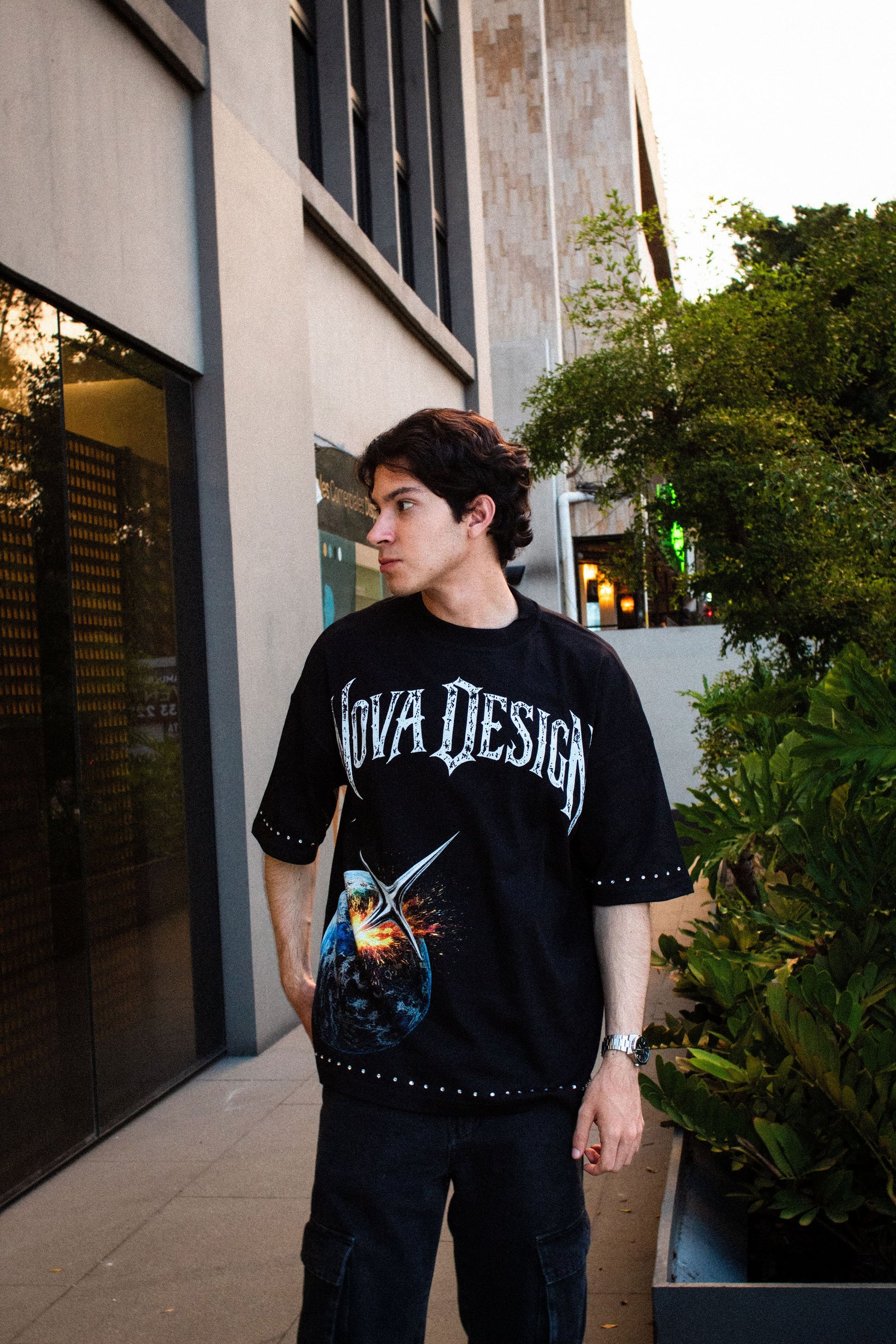 Playera streetwear negra con diseño espacial, pedrería en mangas y corte over